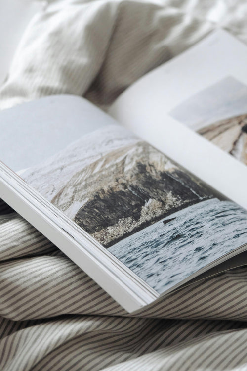 Open book with nature themed pages on a textured fabric background