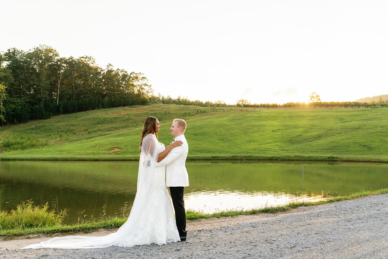 Bride and Groom standing by a pond with a scenic background