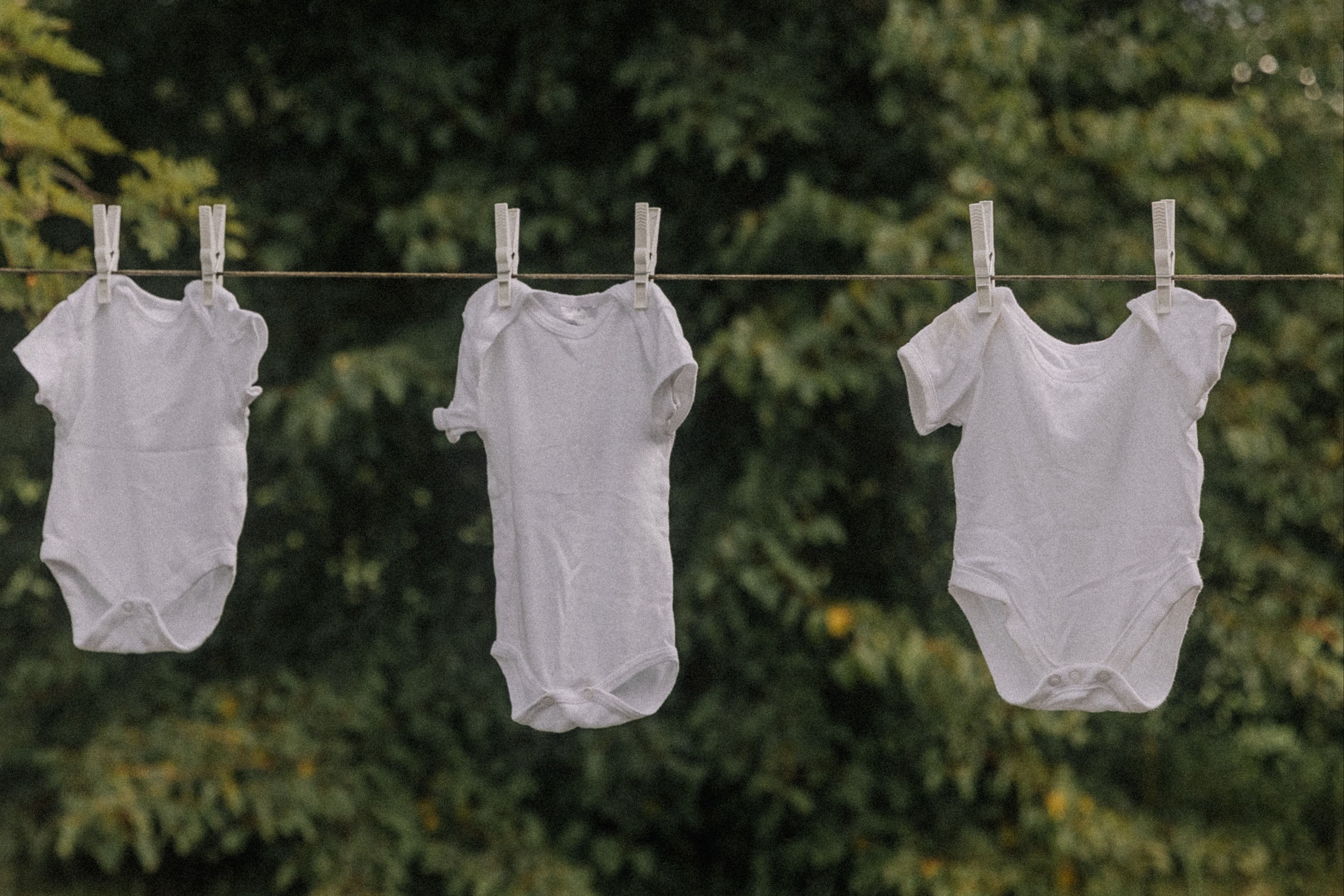 white baby onesies hanging on a clothesline 